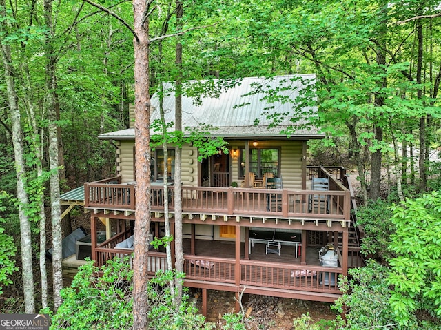 rear view of property with metal roof, a wooden deck, log exterior, and stairway