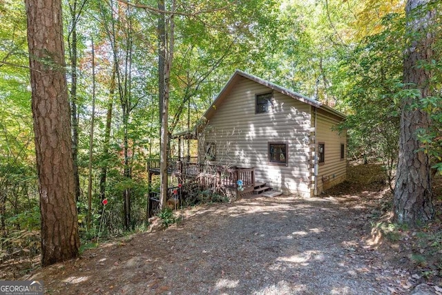 view of side of property with a wooded view and a wooden deck