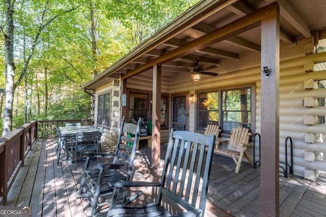 wooden terrace featuring outdoor dining area and a ceiling fan