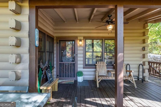 view of exterior entry featuring a wooden deck and ceiling fan