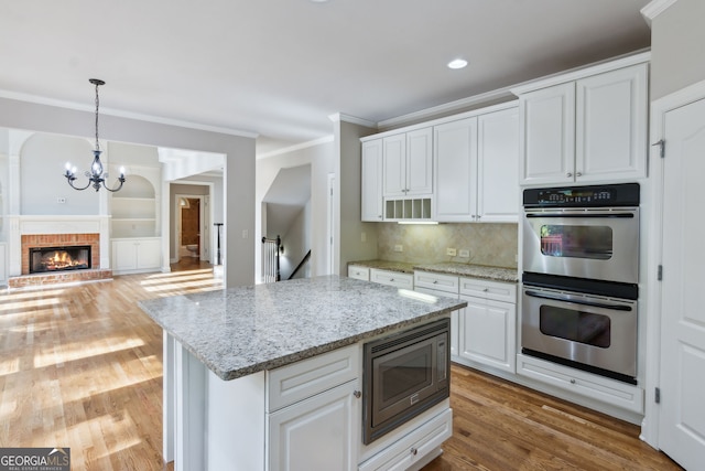 kitchen with decorative backsplash, appliances with stainless steel finishes, white cabinets, and light hardwood / wood-style floors