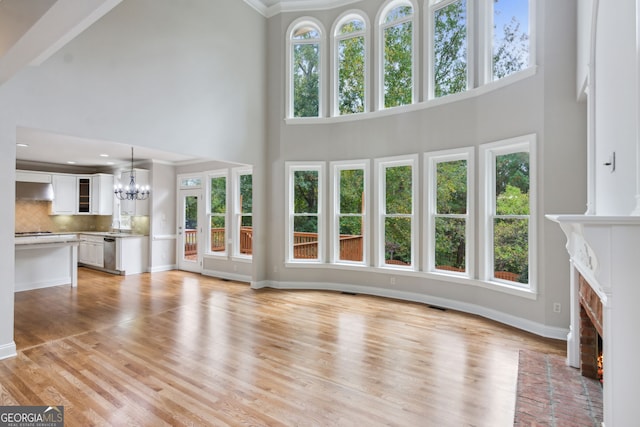 unfurnished living room with light hardwood / wood-style floors, a high ceiling, and plenty of natural light