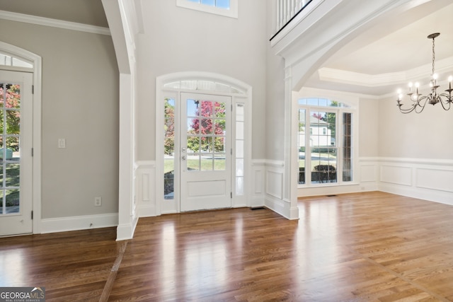 foyer with an inviting chandelier, crown molding, hardwood / wood-style flooring, and a healthy amount of sunlight