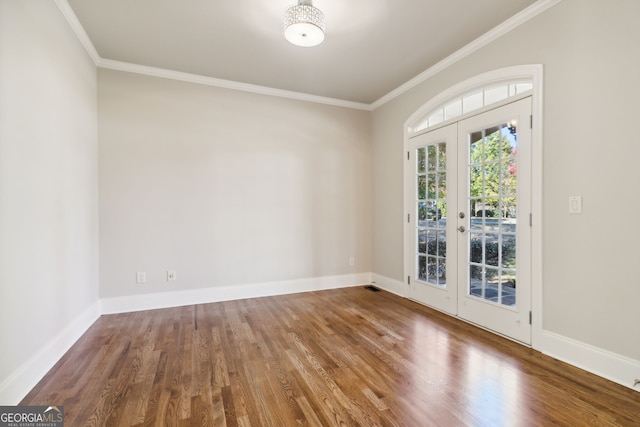 empty room featuring french doors, hardwood / wood-style floors, and crown molding