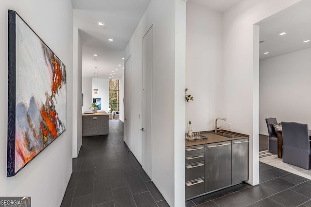 corridor with recessed lighting, a sink, and dark tile patterned flooring