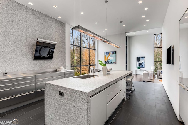 kitchen with recessed lighting, a kitchen island with sink, a sink, and modern cabinets