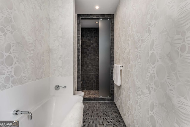 bathroom with wallpapered walls, toilet, tile patterned floors, a garden tub, and a tile shower