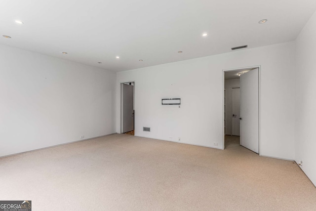 spare room featuring light colored carpet, visible vents, and recessed lighting