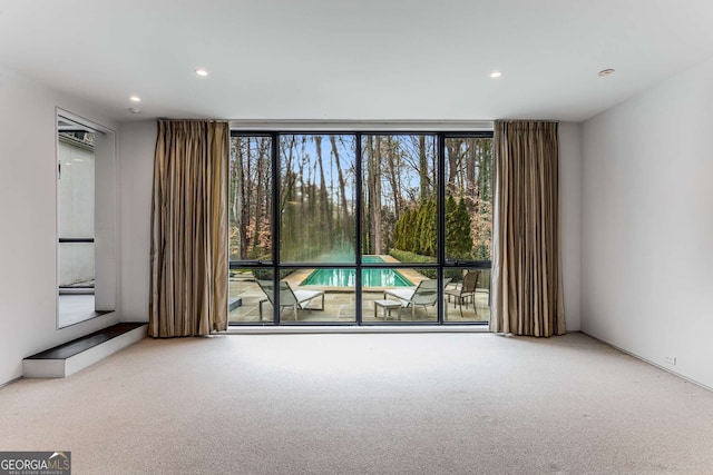 carpeted spare room with floor to ceiling windows and recessed lighting