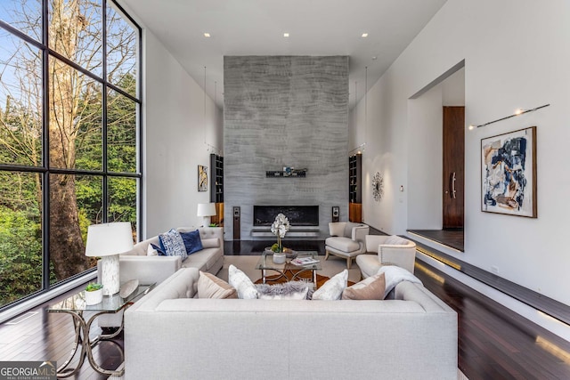 living area with hardwood / wood-style floors, a tile fireplace, a high ceiling, and floor to ceiling windows