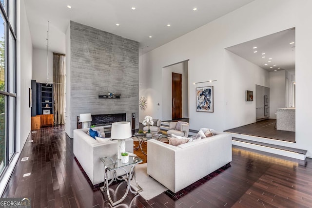 living room featuring a fireplace, a high ceiling, wood finished floors, and recessed lighting