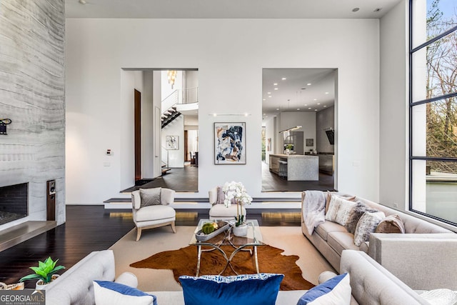 living area featuring floor to ceiling windows, recessed lighting, stairway, a large fireplace, and wood finished floors