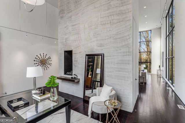 living area with a high ceiling, a wall of windows, wood finished floors, and recessed lighting