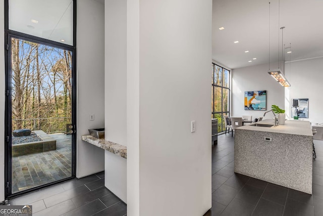 kitchen featuring decorative light fixtures, recessed lighting, expansive windows, an island with sink, and modern cabinets