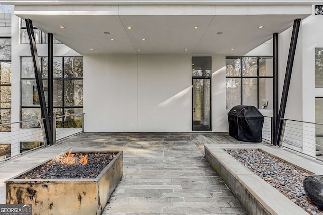 wooden terrace with a fire pit, a patio, and area for grilling