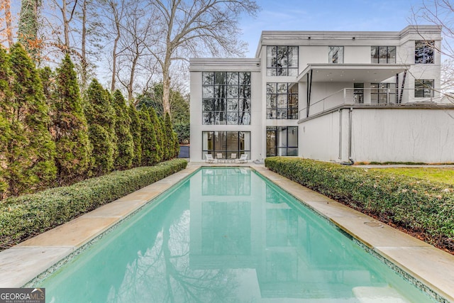 back of house featuring an outdoor pool and stucco siding