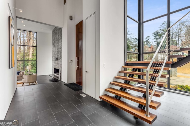 staircase with a fireplace and a high ceiling