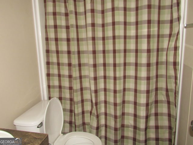 bathroom featuring curtained shower and toilet