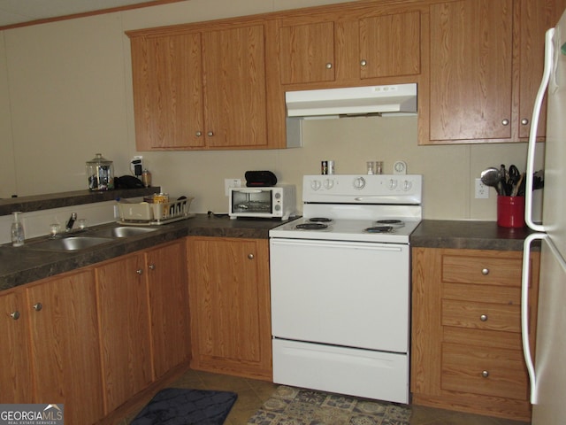 kitchen with dark tile patterned floors, sink, and white appliances