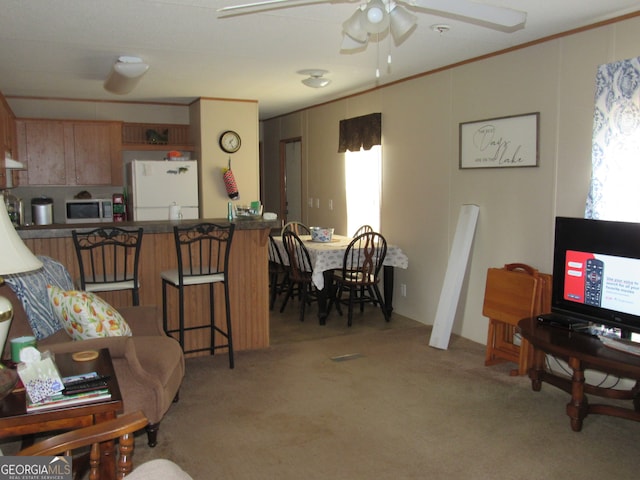 carpeted living room featuring ceiling fan, a healthy amount of sunlight, and ornamental molding