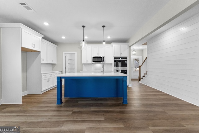 kitchen with appliances with stainless steel finishes, white cabinetry, and hanging light fixtures