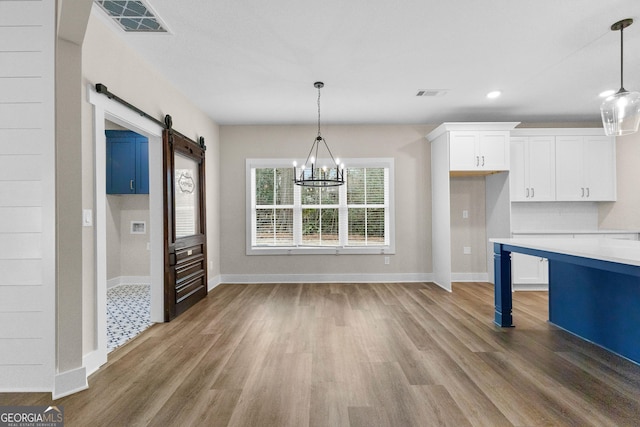 kitchen with a barn door, white cabinetry, decorative light fixtures, and a notable chandelier