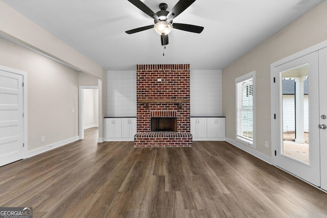 unfurnished living room featuring a fireplace, dark hardwood / wood-style flooring, plenty of natural light, and ceiling fan