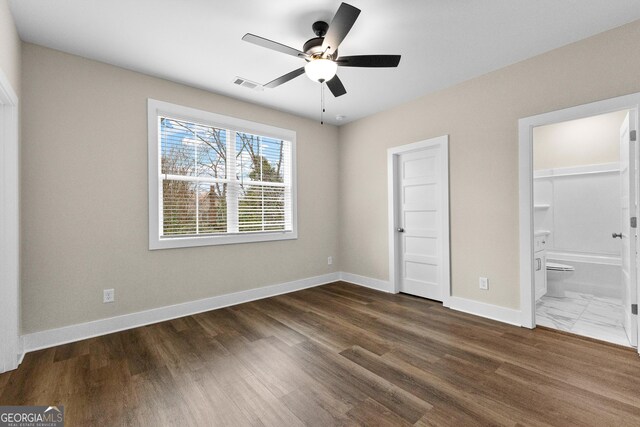 unfurnished bedroom featuring ensuite bath, ceiling fan, and dark hardwood / wood-style floors