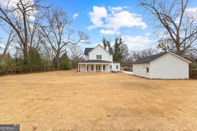 back of house featuring a porch and an outbuilding