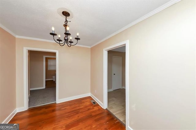 unfurnished dining area featuring dark wood-type flooring, ornamental molding, and an inviting chandelier