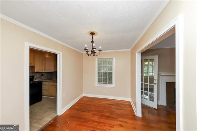 unfurnished dining area featuring crown molding, a textured ceiling, an inviting chandelier, and dark hardwood / wood-style floors