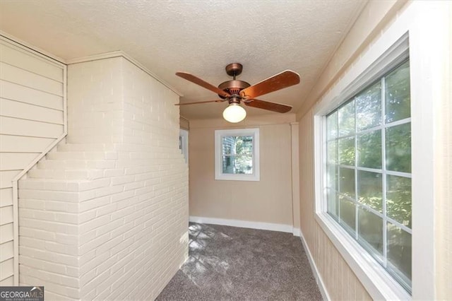 interior space featuring ceiling fan, a textured ceiling, and dark carpet