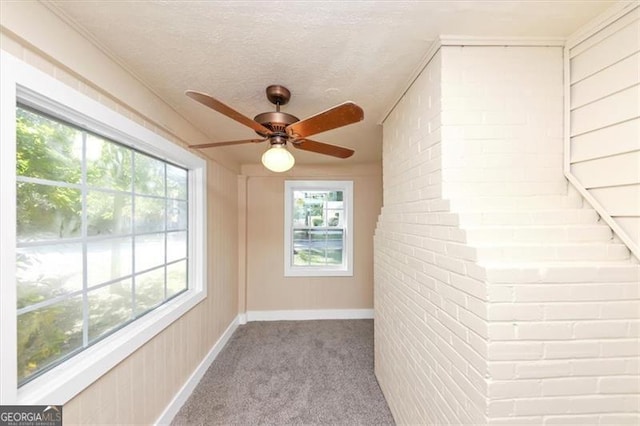 interior space with a textured ceiling, light colored carpet, and ceiling fan