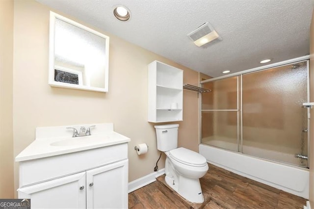 full bathroom featuring a textured ceiling, hardwood / wood-style floors, toilet, enclosed tub / shower combo, and vanity