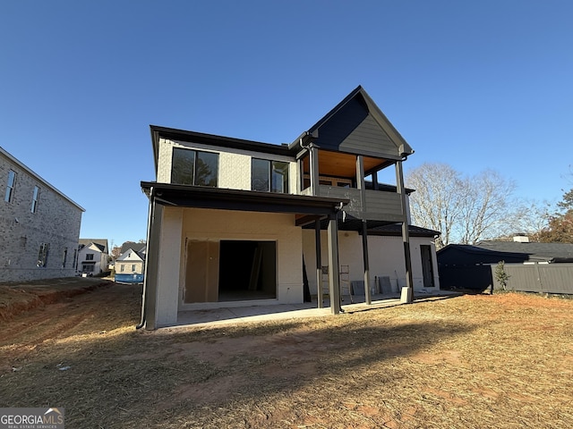 rear view of property with ceiling fan, a balcony, and a patio