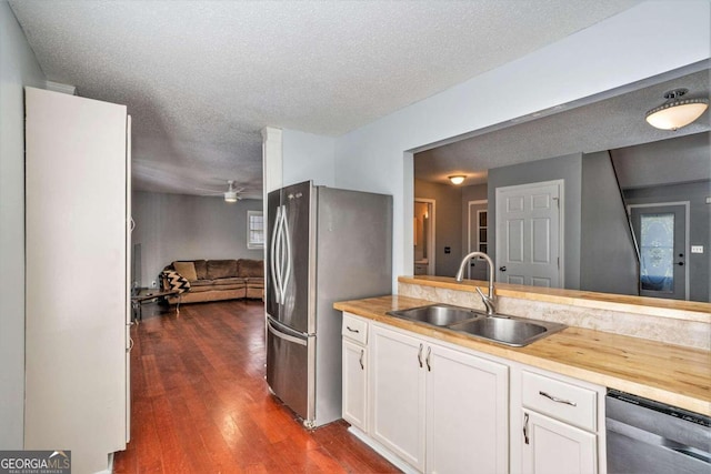 kitchen with white cabinets, dark wood-type flooring, sink, stainless steel appliances, and butcher block countertops