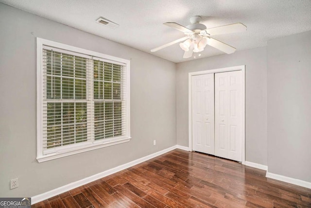 unfurnished bedroom with dark hardwood / wood-style flooring, a textured ceiling, a closet, and ceiling fan