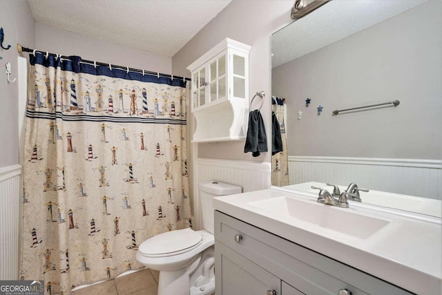 bathroom featuring toilet, tile patterned flooring, a shower with curtain, vanity, and a textured ceiling