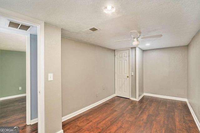 basement with ceiling fan, a textured ceiling, and dark hardwood / wood-style flooring