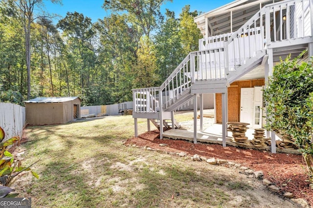 view of yard with a wooden deck, a storage shed, and a patio area