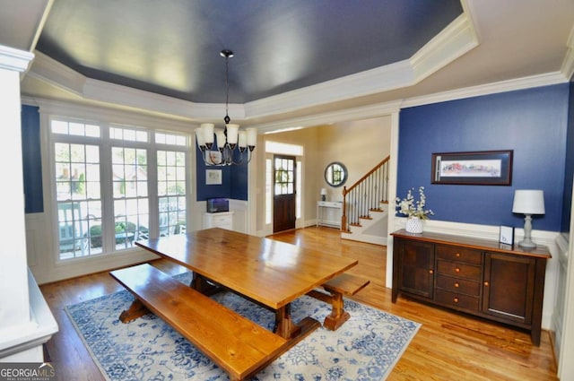 dining area featuring ornamental molding, a chandelier, light hardwood / wood-style flooring, and a raised ceiling