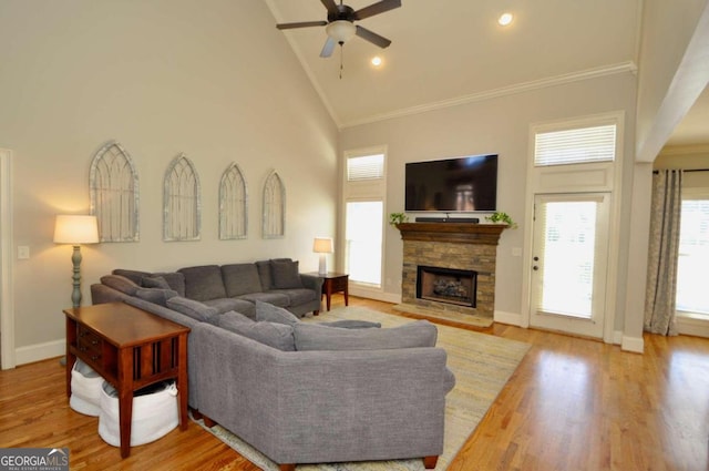 living room with ceiling fan, high vaulted ceiling, ornamental molding, a fireplace, and light hardwood / wood-style floors