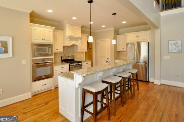 kitchen with light stone counters, stainless steel appliances, light hardwood / wood-style flooring, and a kitchen island with sink