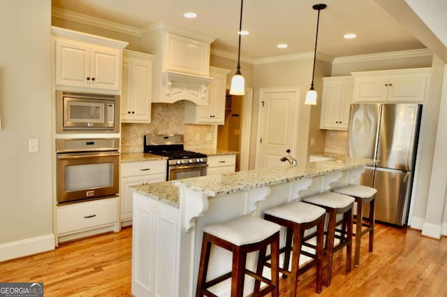 kitchen featuring hanging light fixtures, appliances with stainless steel finishes, light stone counters, and light wood-type flooring