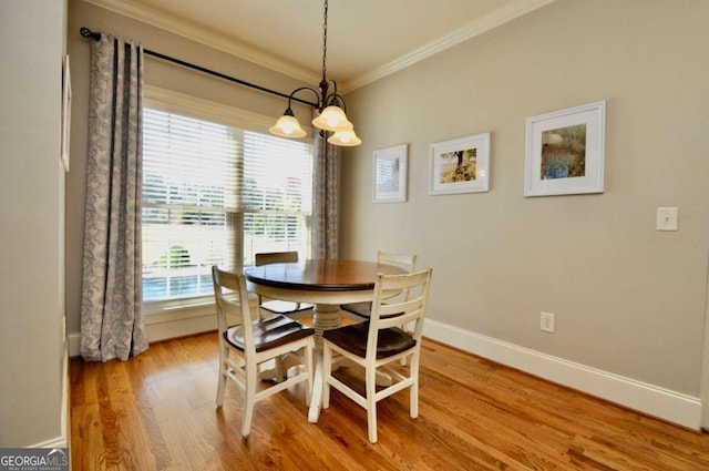 dining area with hardwood / wood-style floors, crown molding, and a chandelier