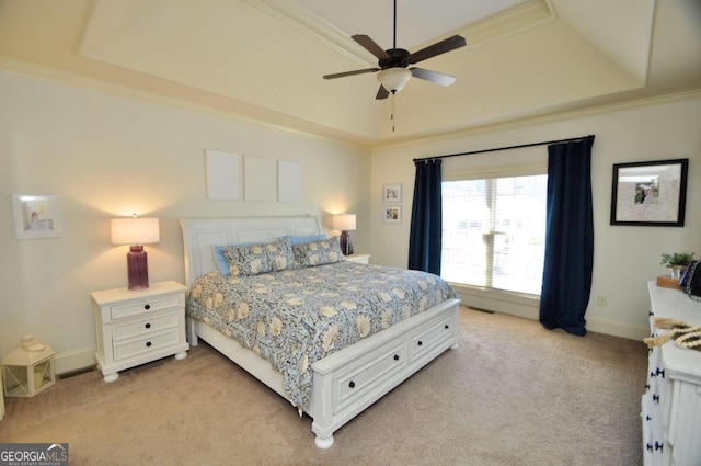 bedroom with ceiling fan, crown molding, a tray ceiling, and light colored carpet