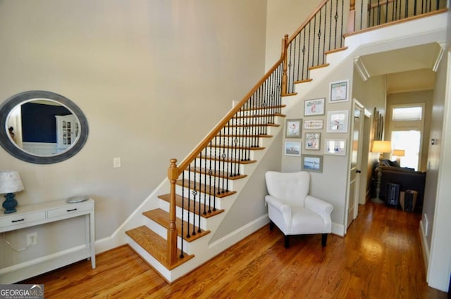 stairs featuring hardwood / wood-style floors and a towering ceiling