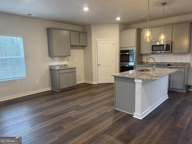 kitchen with decorative light fixtures, sink, light stone countertops, gray cabinetry, and stainless steel appliances