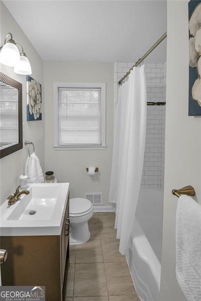 full bathroom featuring tile patterned floors, shower / bath combo with shower curtain, vanity, and toilet