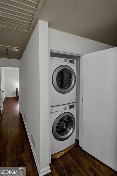 clothes washing area with dark hardwood / wood-style floors and stacked washer / dryer